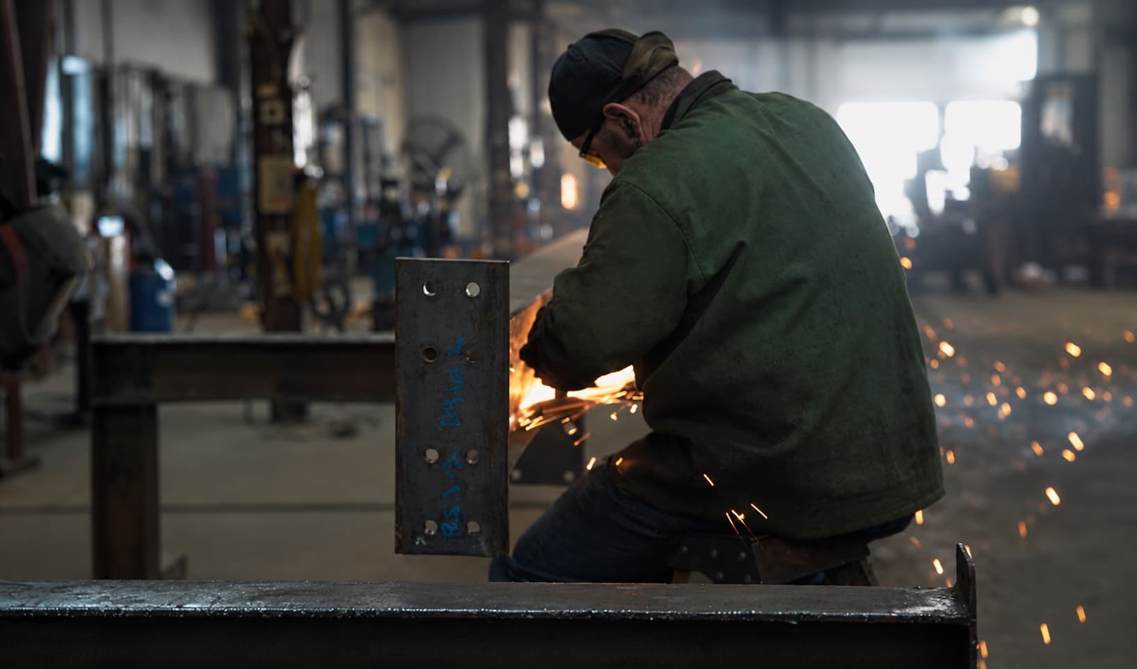 A welder fabricating a steel beam at a Heartland client's shop